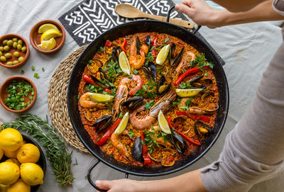 Spanish paella in large pot on dining room table with lemon garnish